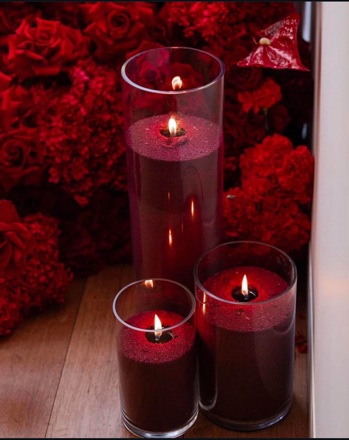 Burgundy candle sand glowing in three clear glass vessels