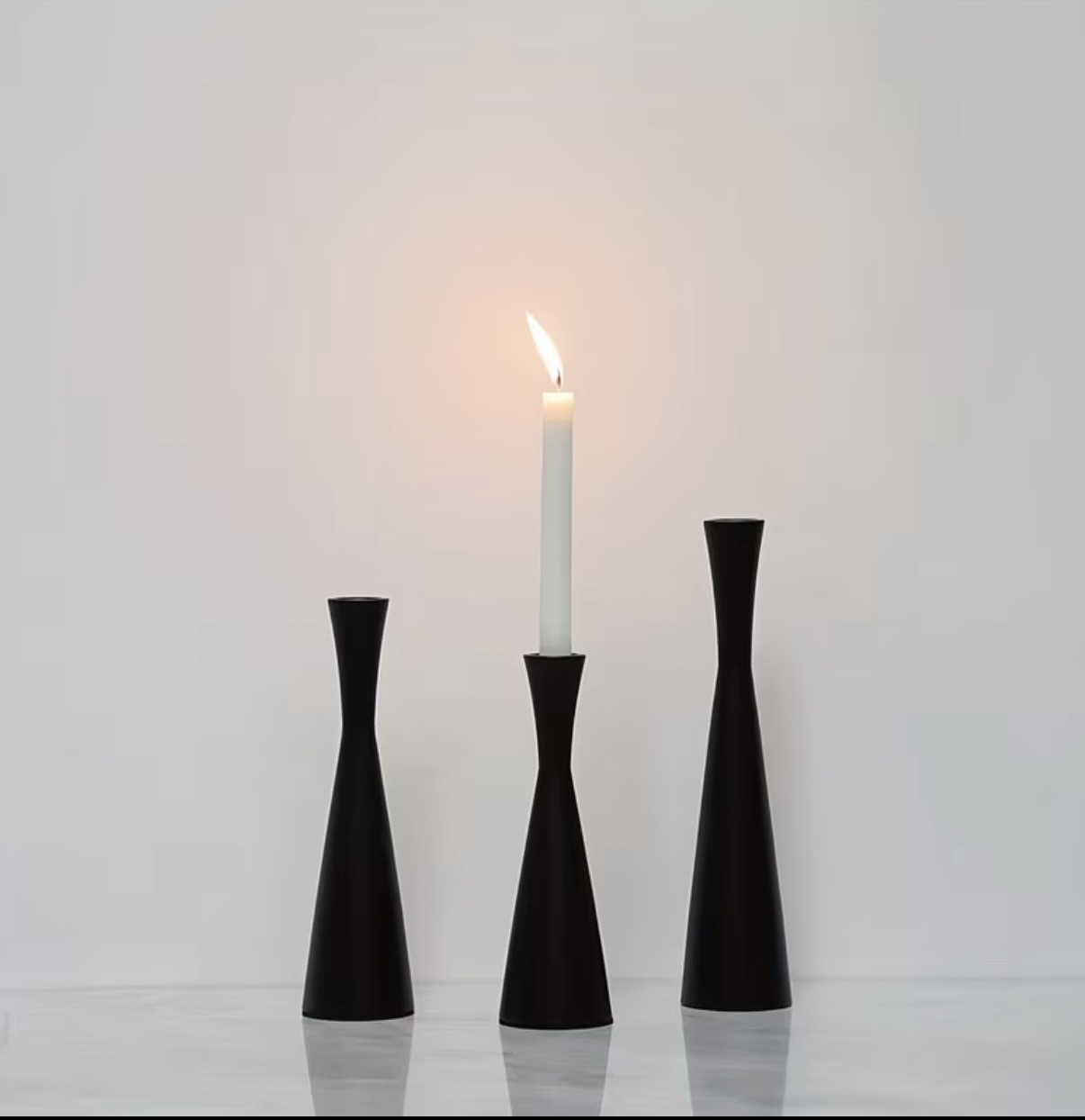 Matte black hourglass candlesticks in three heights on marble