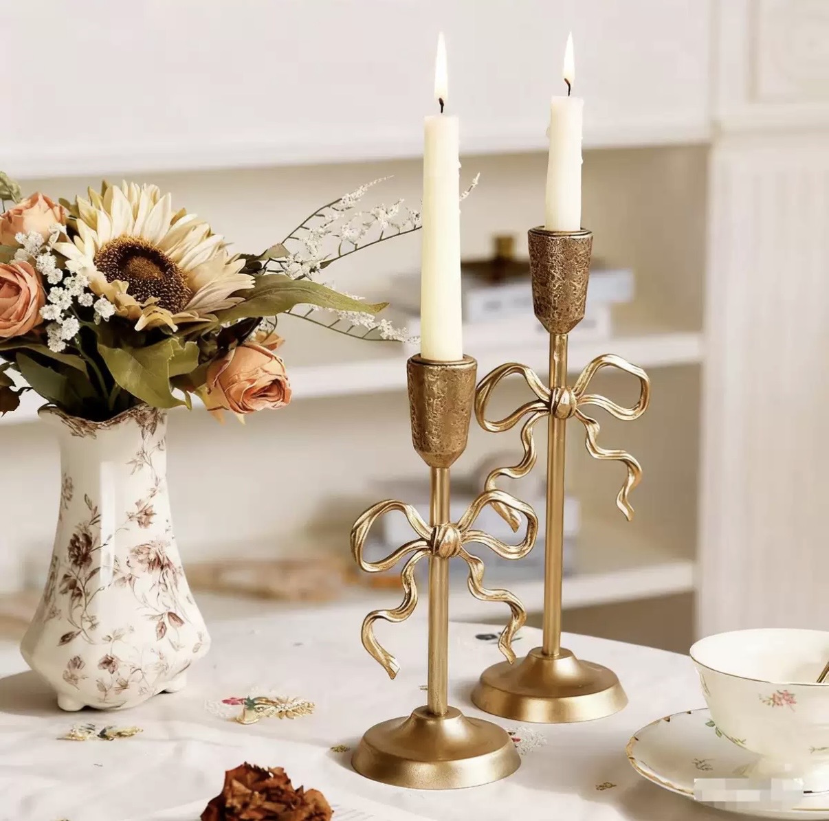 Gold bow-detail candlesticks with textured cups and lit taper candles