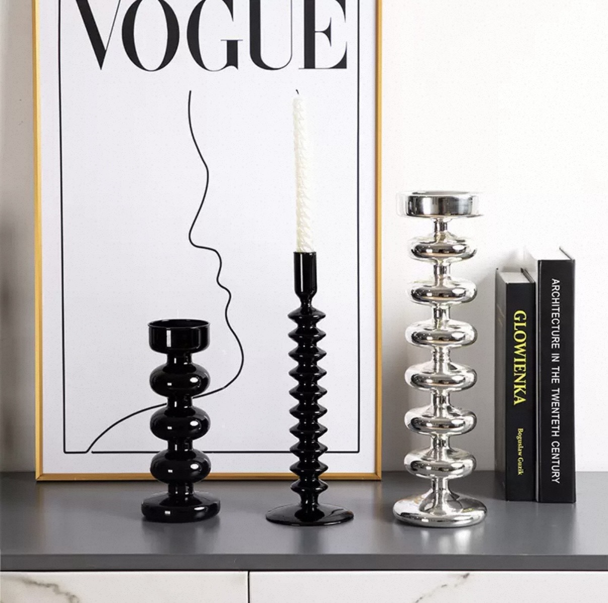 Glossy black and silver ribbed glass candle holders beside books