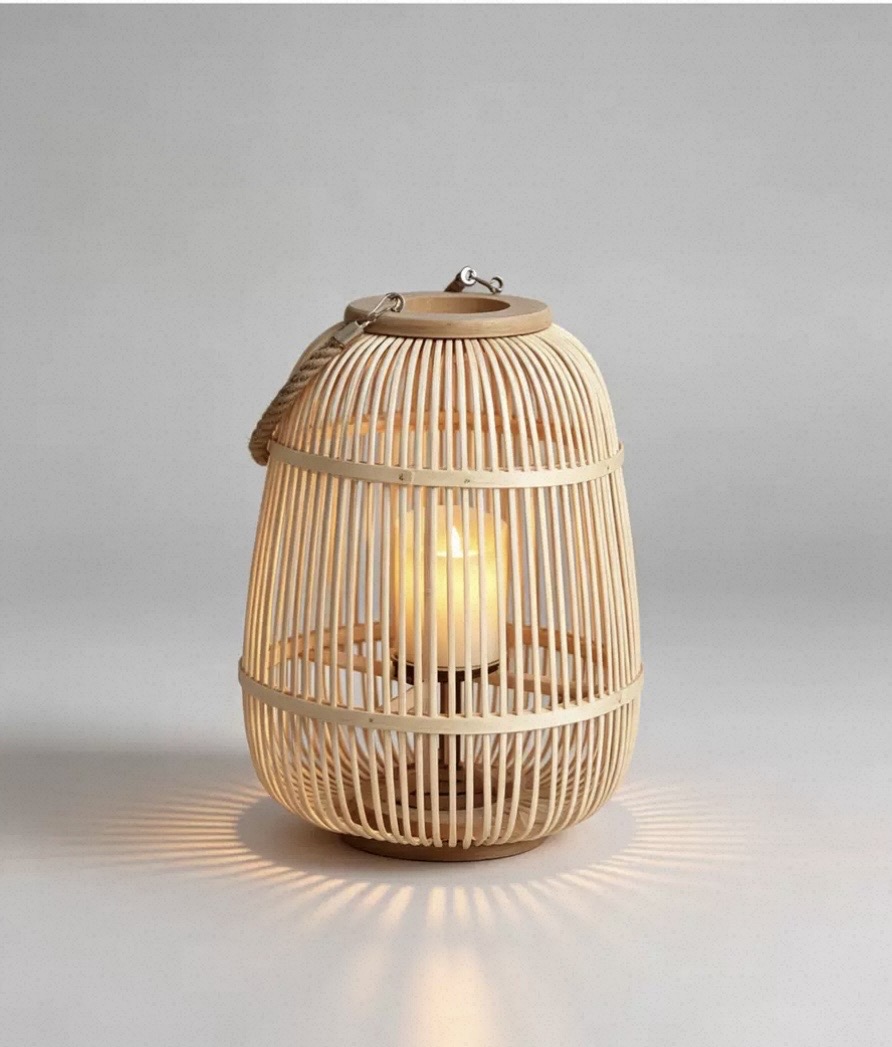 Bamboo cage lantern with rope handle and a lit pillar candle