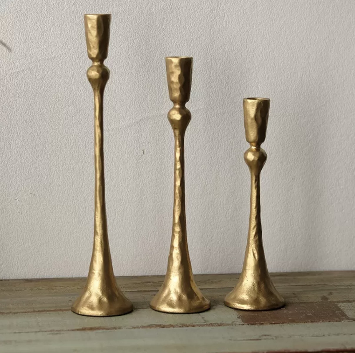 Hammered gold candlesticks in three heights on a rustic table