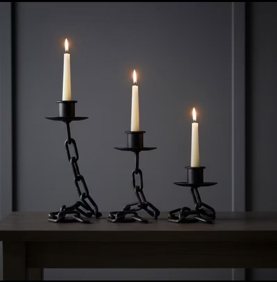 Black chain-link candlesticks with lit taper candles in three heights