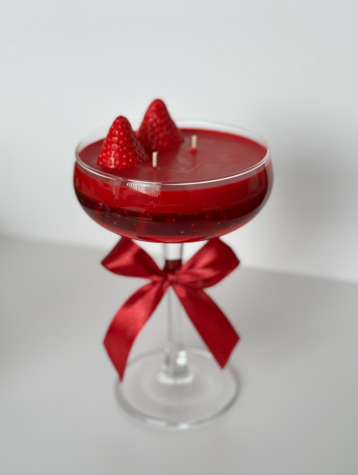 Strawberry Spritz Coupe Candle — Deep red spritz with sculpted strawberries and a satin bow.