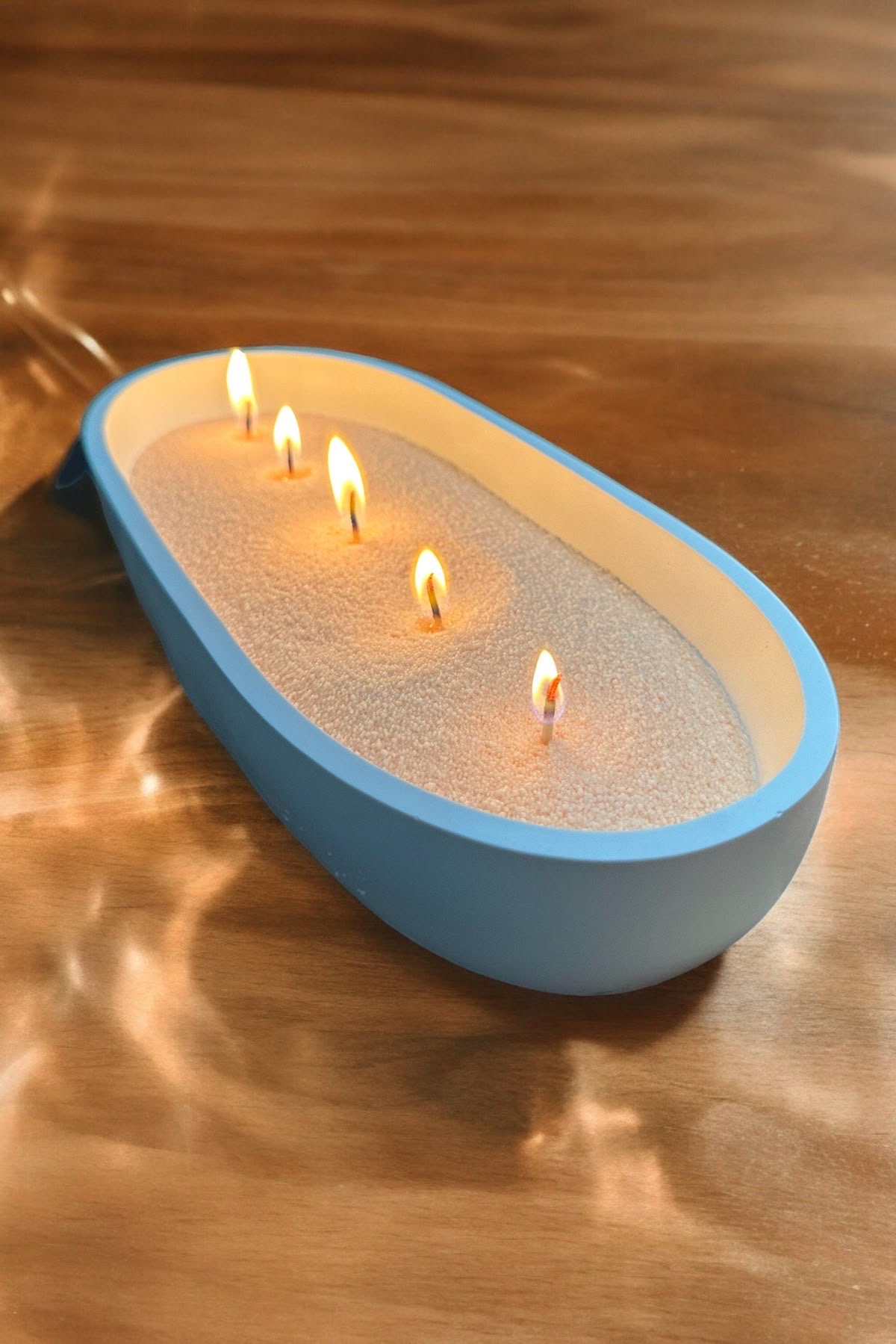 Ivory candle sand with five flames in a blue oval vessel