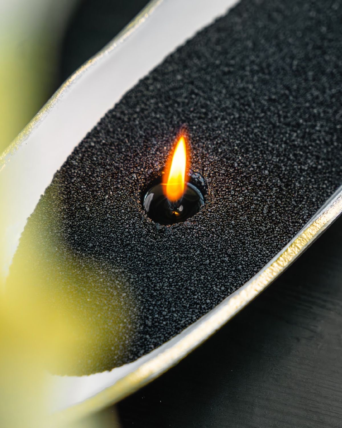 Black candle sand burning in a long sculptural vessel