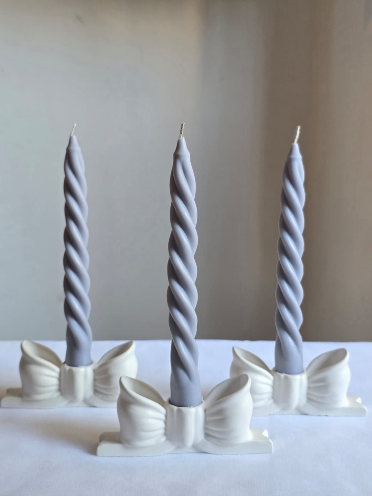 Ivory Bow Taper Candle — A twisted taper resting in a sculpted bow.